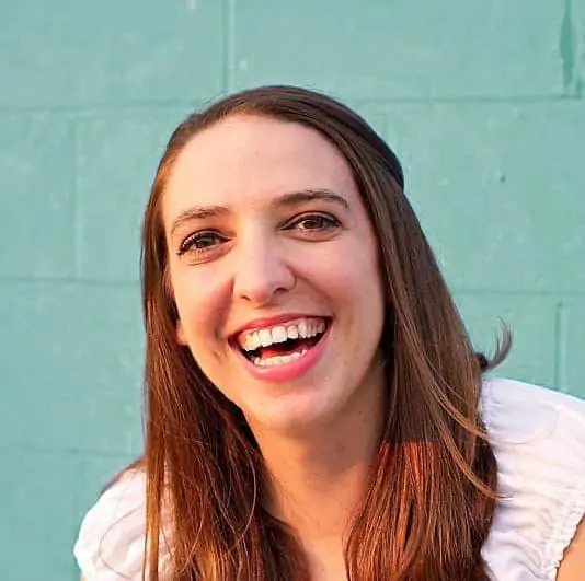 woman with brown hair smiling at the camera in front of a blue wall