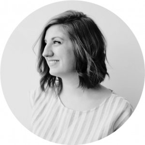 black and white photo of women with short hair wearing a striped blouse looking to the side and smiling