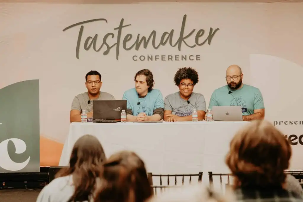 four people sitting at a table with the tastemaker logo behind them