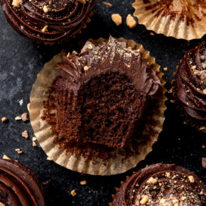 sideways chocolate cupcake half eaten on top of a wrapper