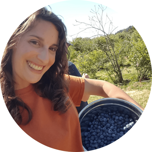 woman holding blueberries with trees behind her
