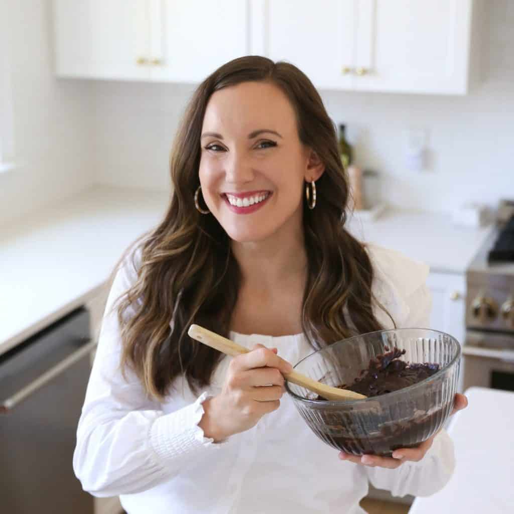 woman in white kitchen and white top stiring a bowl