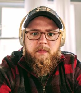man in a hat and headphone looking to the camera
