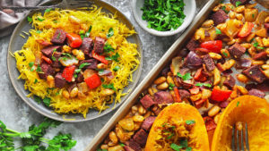 spaghetti squah on a plate with toppings next to roasted vegetables and squash