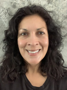 woman in black shirt with brown curly hair smiling