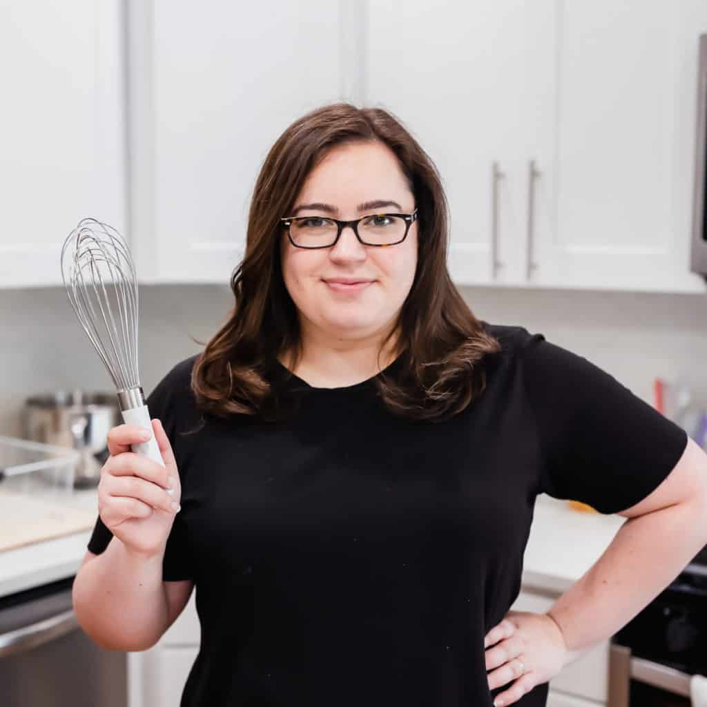 woman standing in a kitchen with a whisk and a black shirt