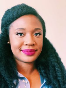 woman with black hair and blue and white shirt smiling