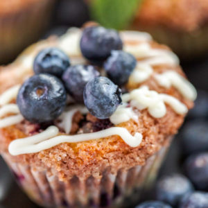 close up of blueberry muffin with blueberries and white frosting
