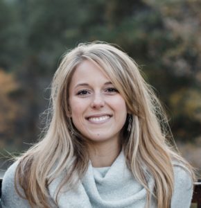 woman in gray sweater and blonde hair smiling outdoors
