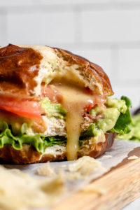 close up of a bitten blt chicken burger with toppings