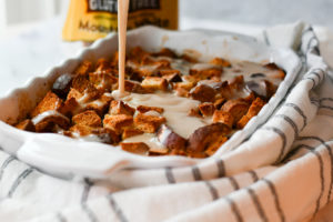 gluten-free bread and butter pudding in a white pan and white frosting drizzling down