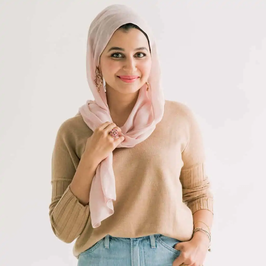 woman in pink headcovering and tan sweater smiling to the camera