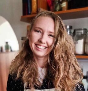 woman with blonde hair and black and white sweater smiling