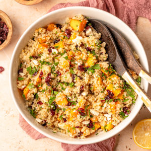 cranberry quinoa salad with toppings in bowl and two wooden spoons