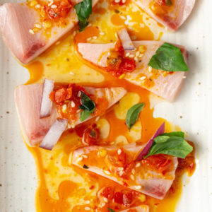 close up of hamachi crudo with toppings on a plate