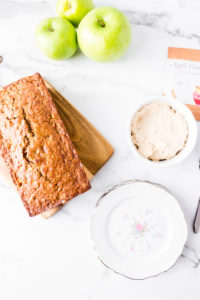 loaf of apple cinnamon oatmeal bread on a board next to three green apples