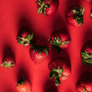 10 strawberries on a red background with water droplets
