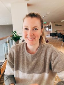 woman with blonde hair in a ponytail wearing a sweater and smiling