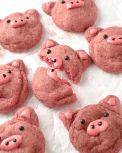 six pink cookies in the shape of pigs