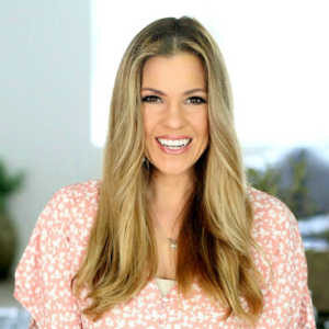 blonde woman wearing a pink and white blouse smiling to the camera