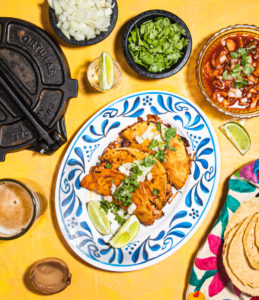 three tacos on a plate with toppings and salsas surrounding