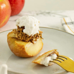 close up of a air fryer baked apple with toppings and a fork