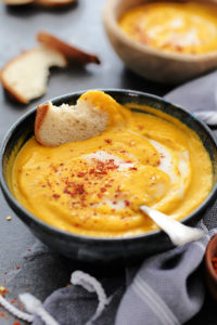 bowl of roasted butternut squash apple soup with a piece of bread and toppings