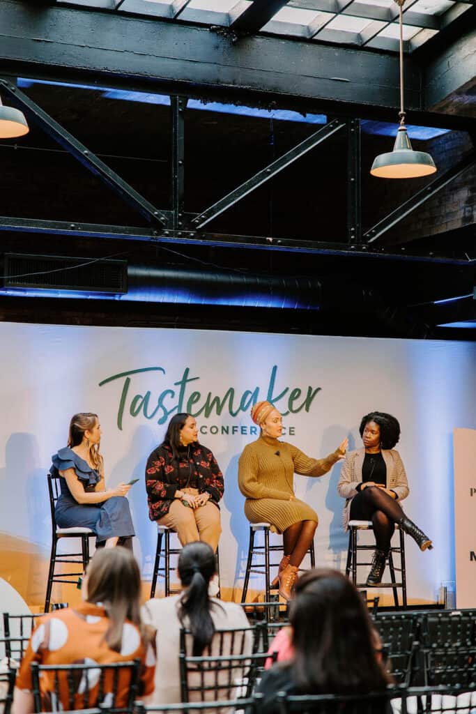 four people sitting in chairs speaking to an audience of people