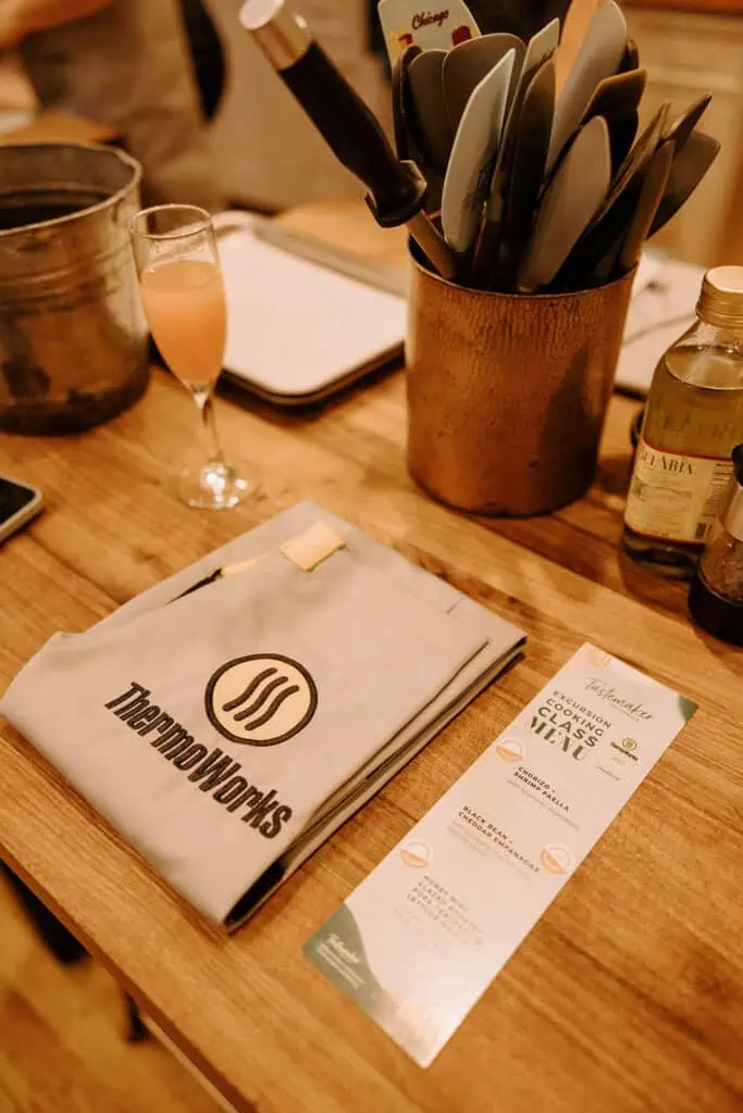 thermoworks apron folded next to. a menu and a glass of champagne