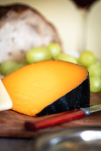 close up of a slice of gouda cheese next to a red knifr