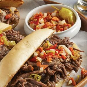 close up of a sandwich with toppings next to a white bowl