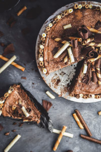 slice of chocolate cake with toppings next to a pan of chocolate cake