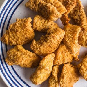 pieces of fried catfish on a white and blue striped plate