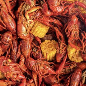 close up of a pile of crawfish with three halves of corn on the cob