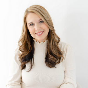 woman with blonde hair wearing a cream turtleneck long sleeve smiling at the camera