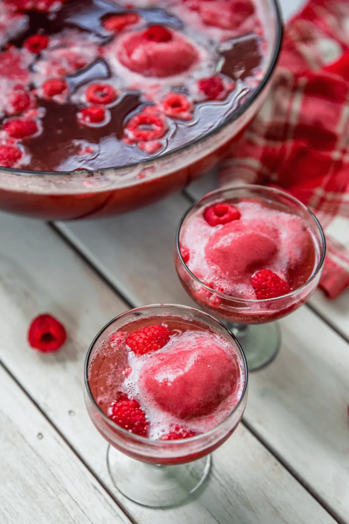 punch in glasses with sorbet and raspberries on wooden backdrop
