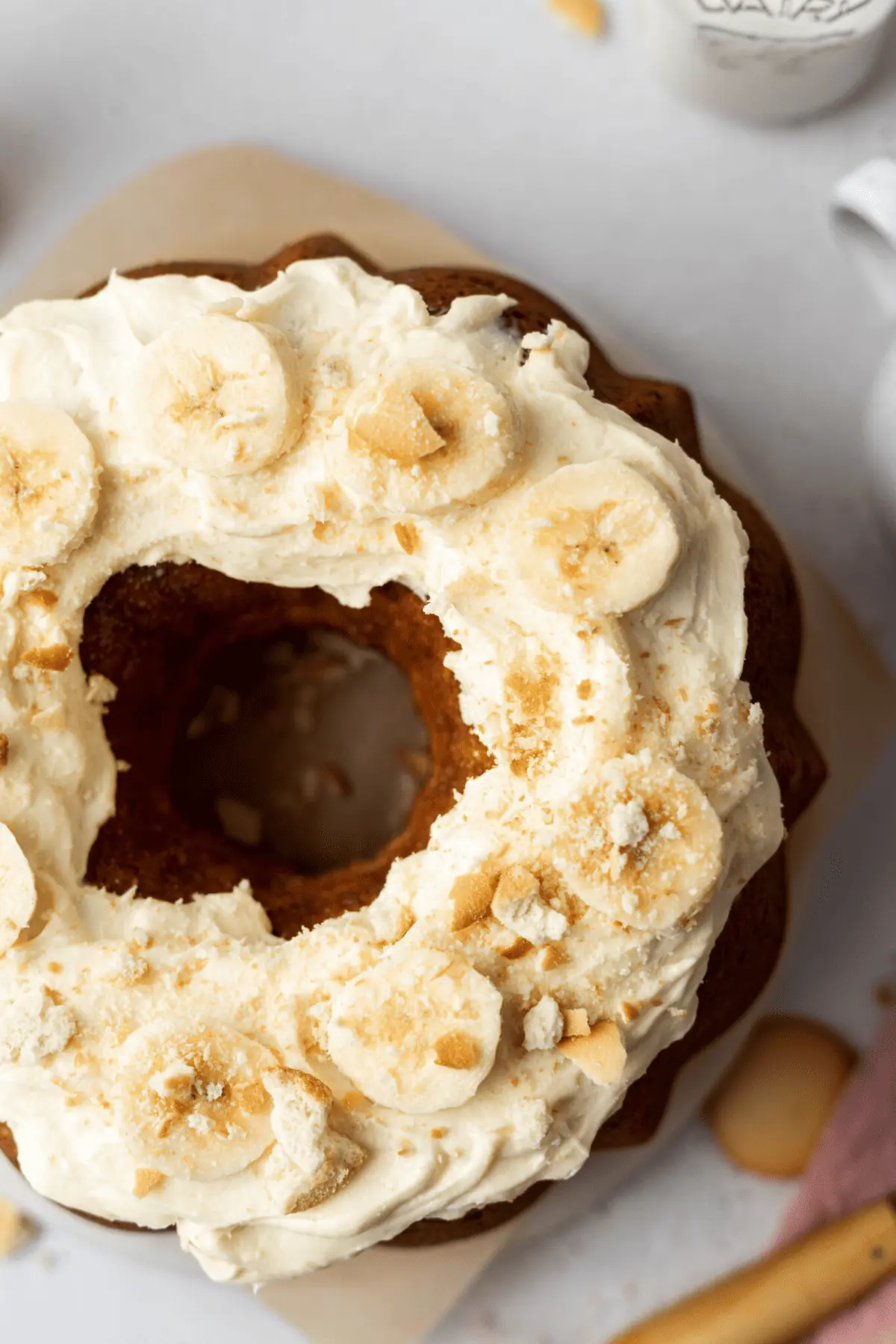 overhead of a bundt cake with a frosting and slices of bananas
 