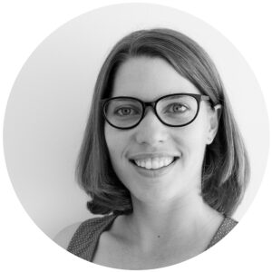 black and white photo of a woman with short hair and black frame glasses
