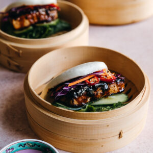 A bao-style sandwich sits in a bamboo steaming basket