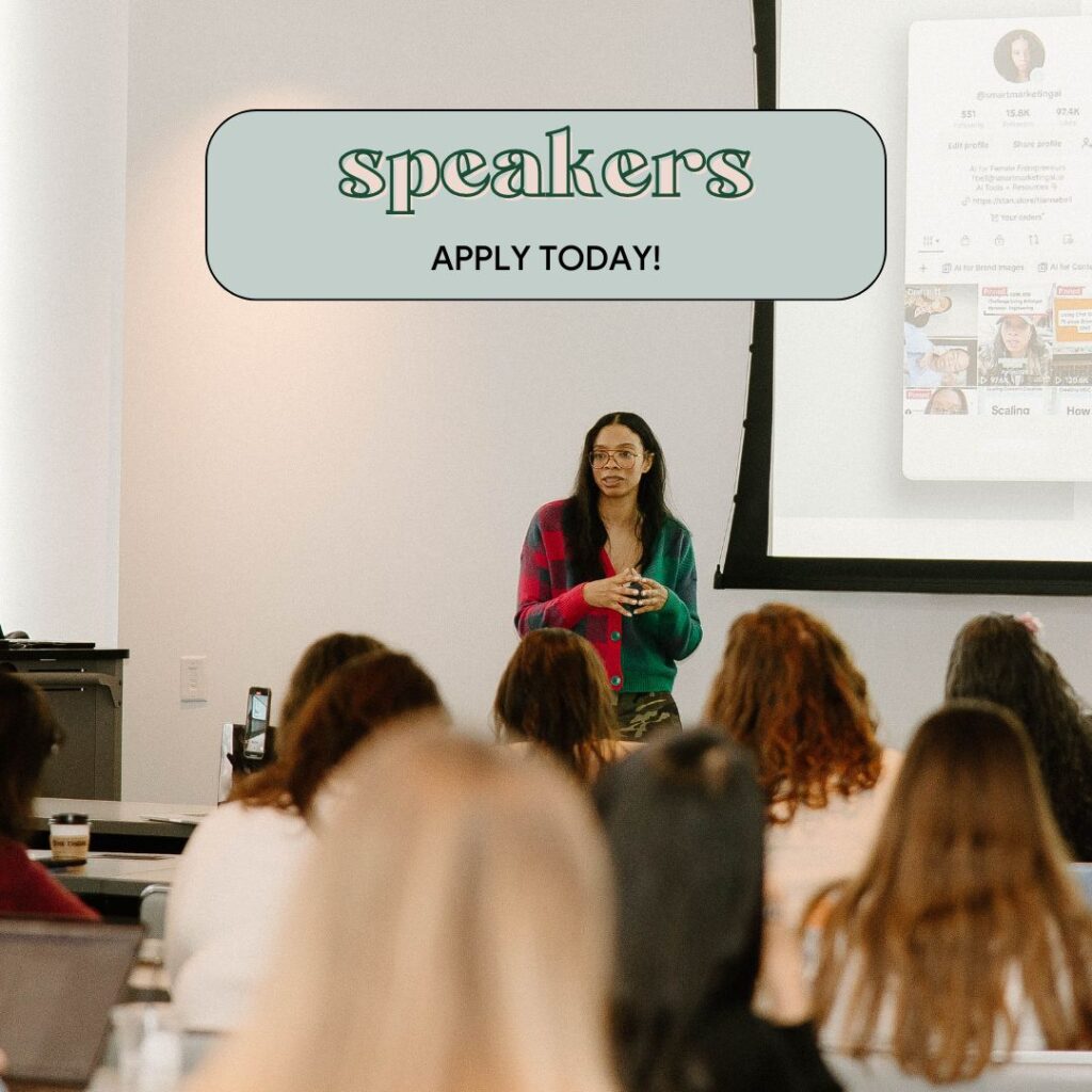 A woman standing and speaking in front of an audience during a presentation, with a projector screen behind her. The text above reads: "Speakers – Apply today!"