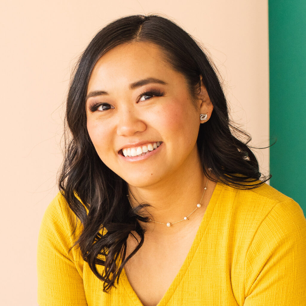 Lisa Childs smiling warmly, wearing a yellow top with pearl jewelry, against a soft peach and green background.