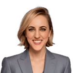 a woman with short blonde hair wearing a gray blazer smiles in front of a white background