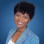 Sandie Markle, a smiling woman with short curly hair, wearing a blue patterned blazer over a white top, posed against a blue background.