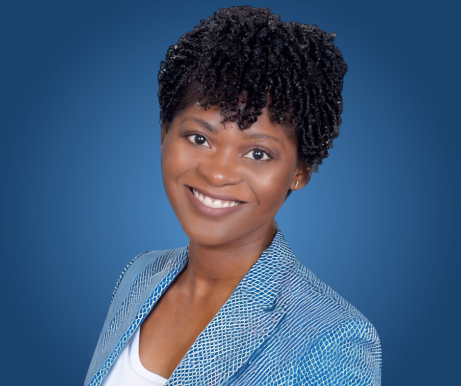 Sandie Markle, a smiling woman with short curly hair, wearing a blue patterned blazer over a white top, posed against a blue background.